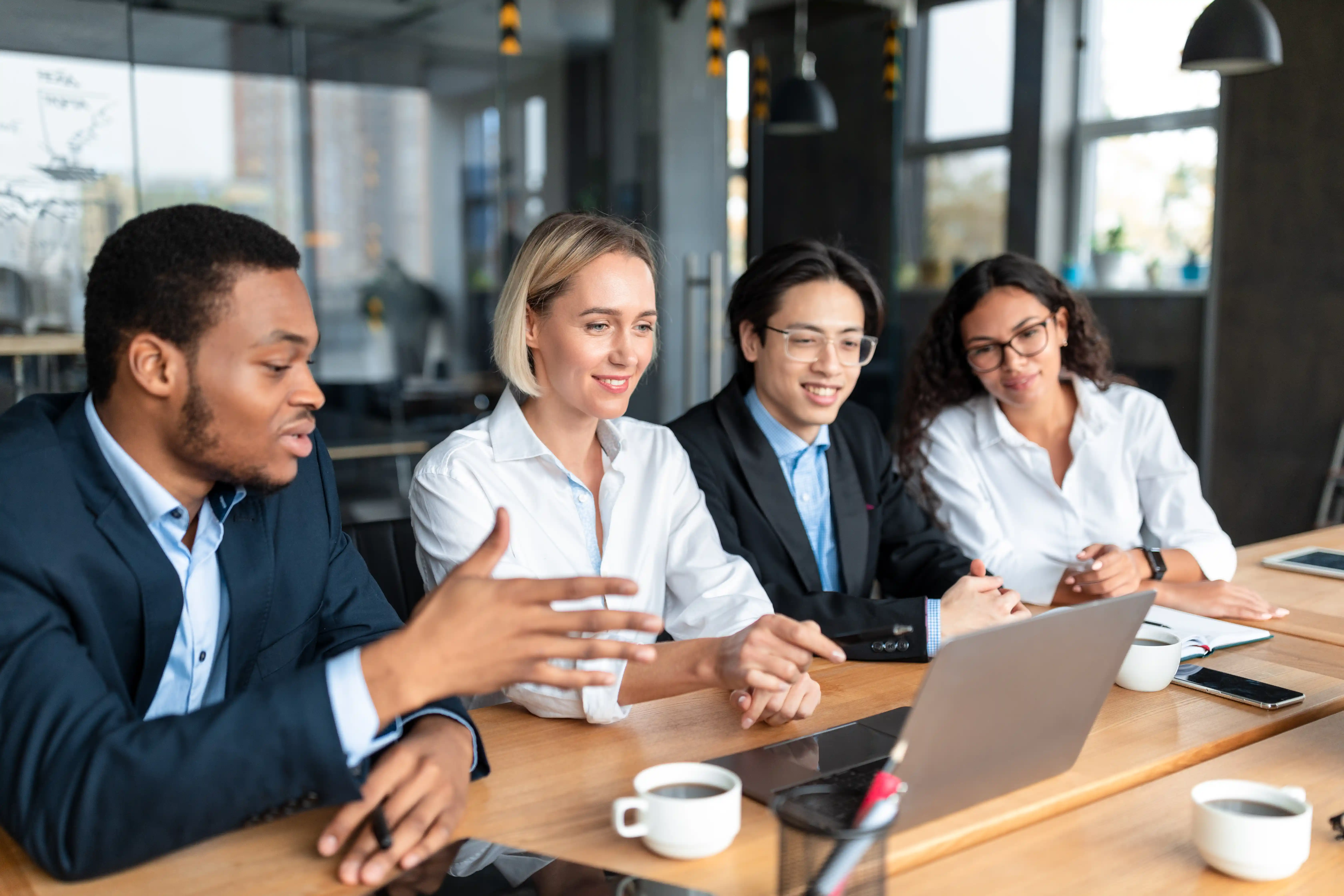 A diverse business team discussing growth strategy around a laptop